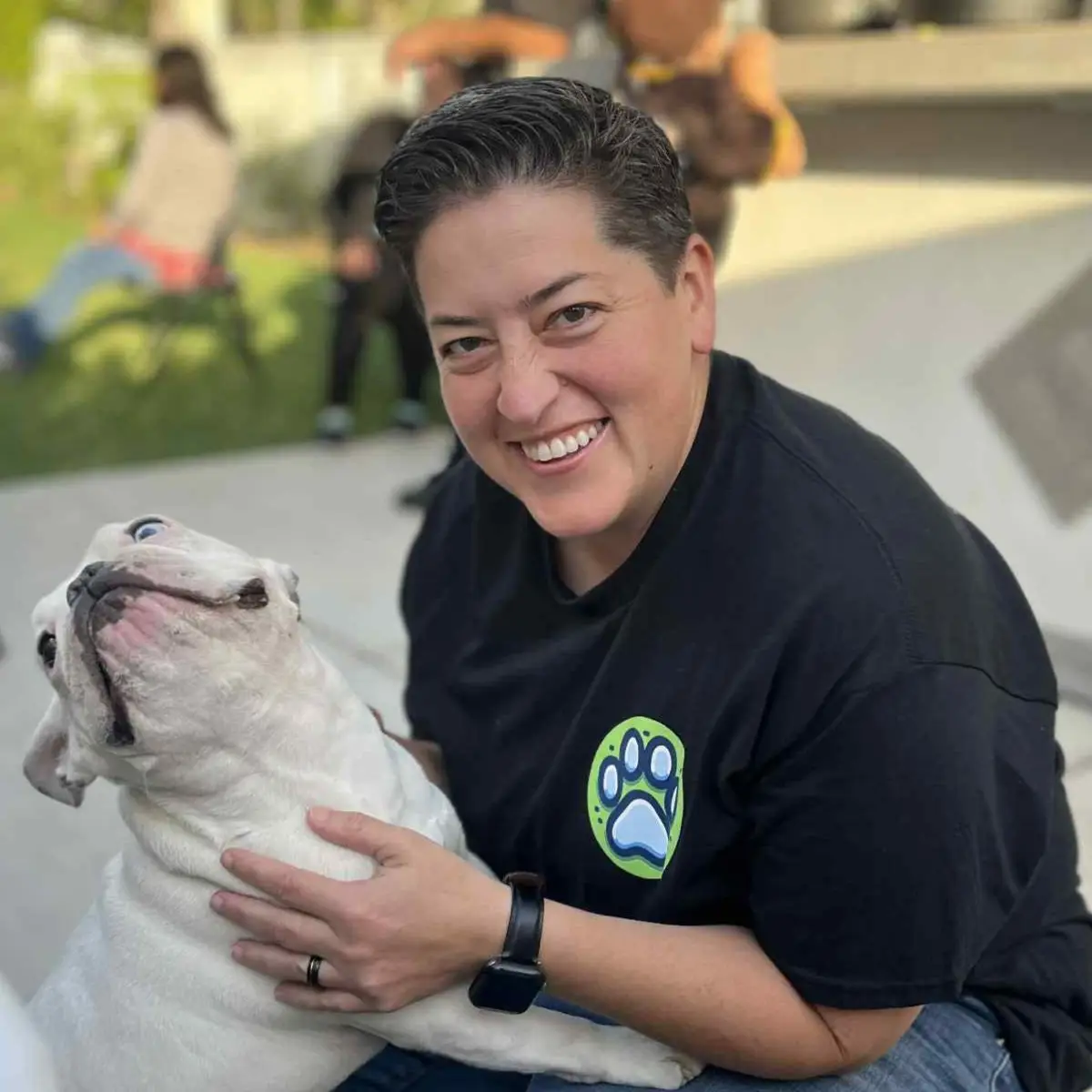A person smiles while holding a dog.