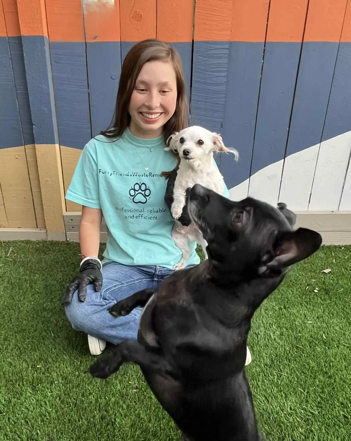 A woman kneeling with two dogs.